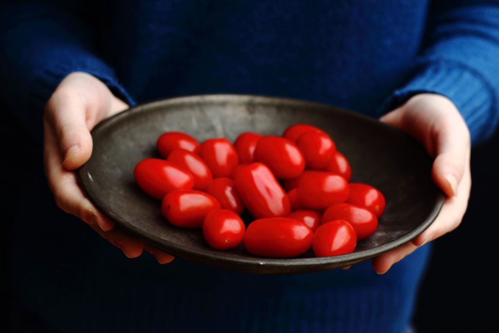 hands holding tomatoes in pewter bowl copy